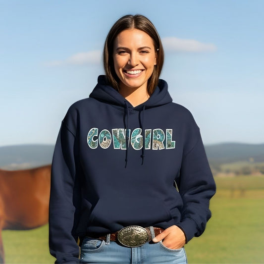 Woman wearing a navy hoodie with 'COWGIRL' printed on it, standing in a field with a horse. Cowgirl Aztec Hoodie for Horse Lovers, Cowgirl Sweatshirt, Equestrian Barn Wear