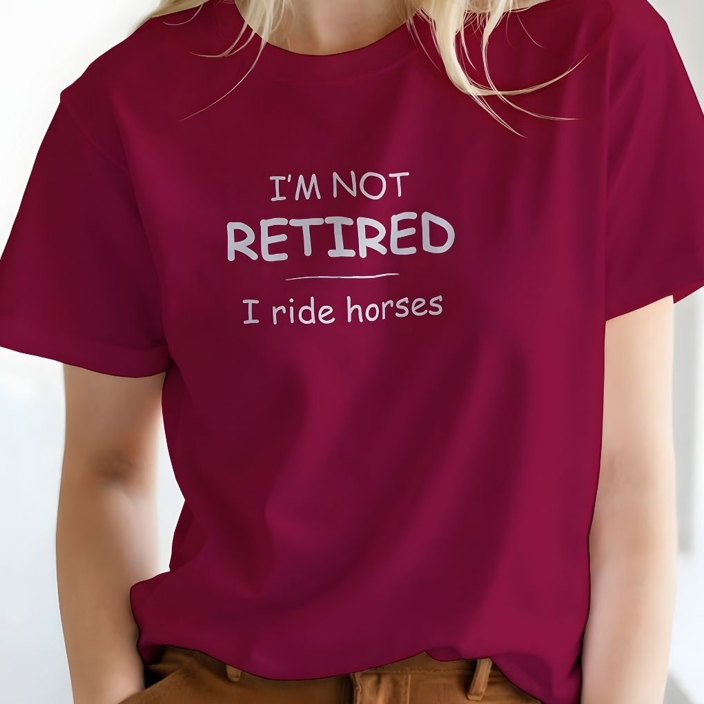 Person wearing a maroon t-shirt with text 'I'm not retired, I ride horses' on a plain background. I'm Not Retired I Ride Horses T-Shirt for Horse Lovers, Equestrian Tee for Trail Riding, perfect gift for horse lovers