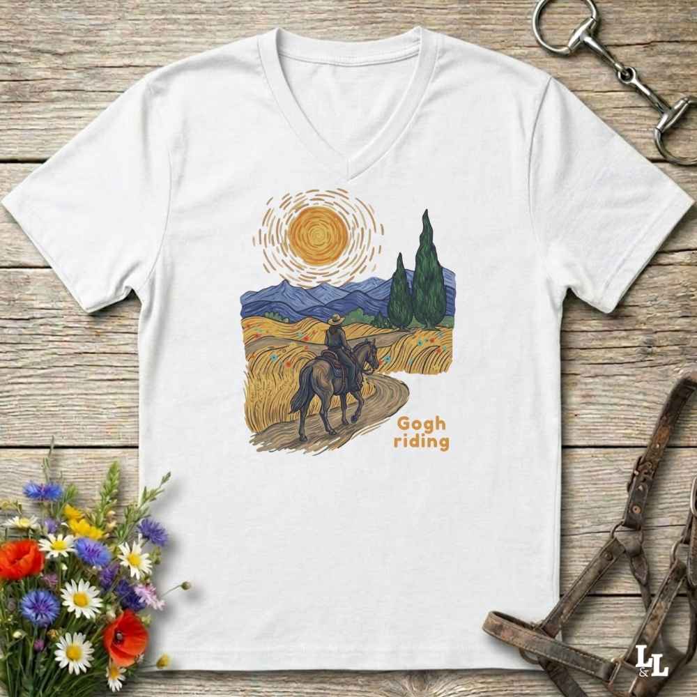 white v-neck tee with van gogh inspired design and the words Gogh Riding, lying on barn style floorboards with flowers and horse halter and horse bit