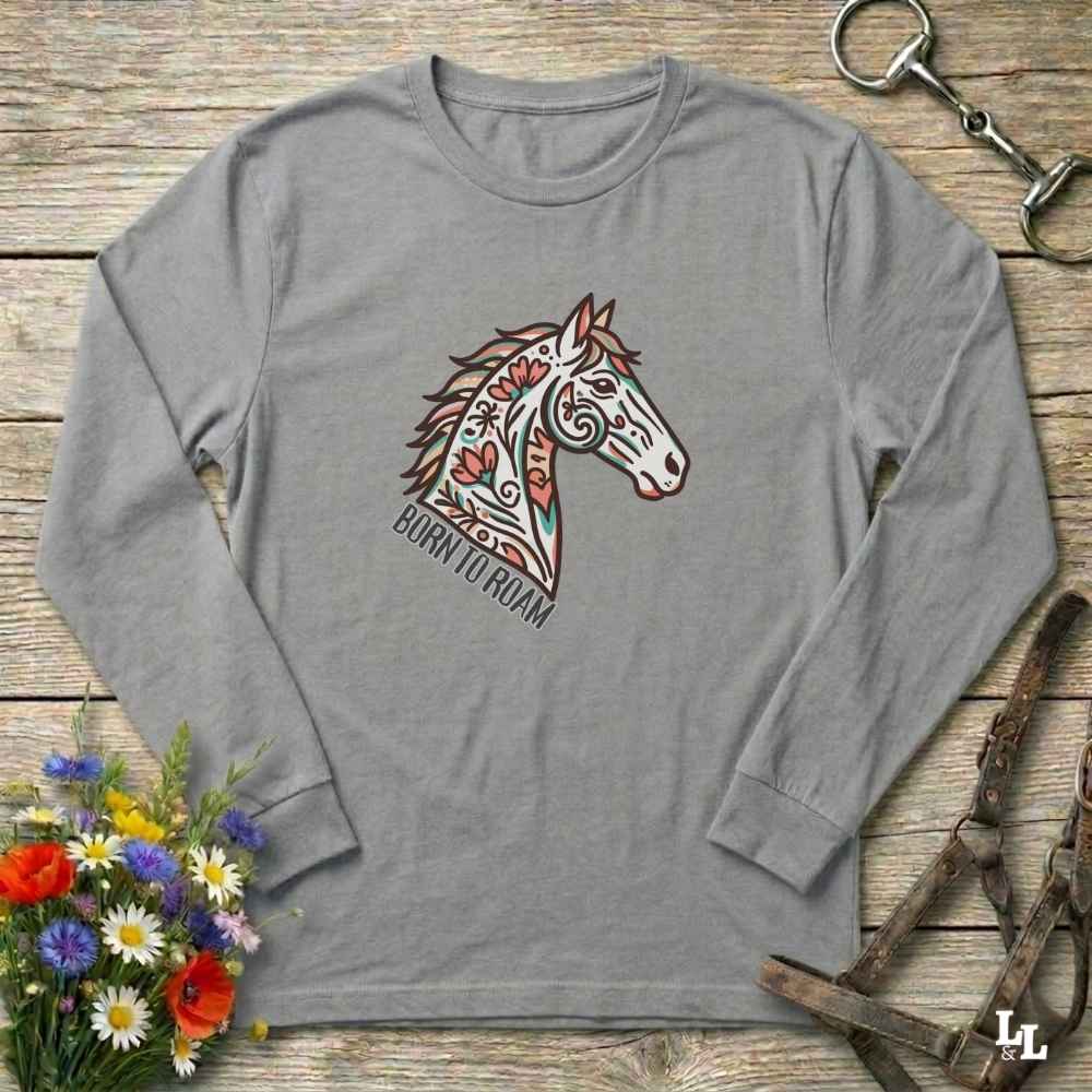 Gray long-sleeve shirt with a colorful horse graphic on a wooden surface with floral and equestrian-themed items.