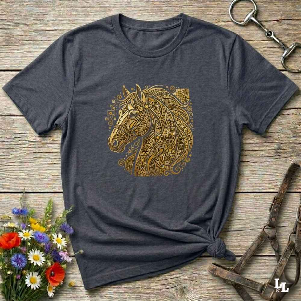 A dark heather gray t-shirt with a gold horse head graphic, styled flat on a rustic wooden background with equestrian accessories and flowers.