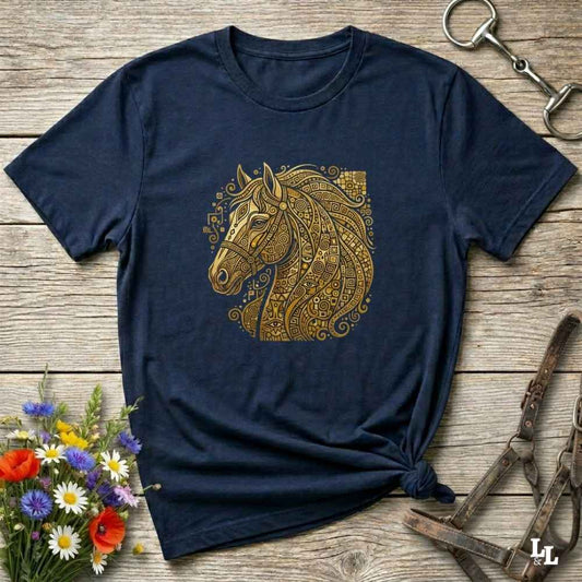 A navy blue short-sleeve t-shirt with a detailed gold horse head graphic on the chest, styled in a flat-lay on a rustic wooden background with equestrian accessories and flowers.