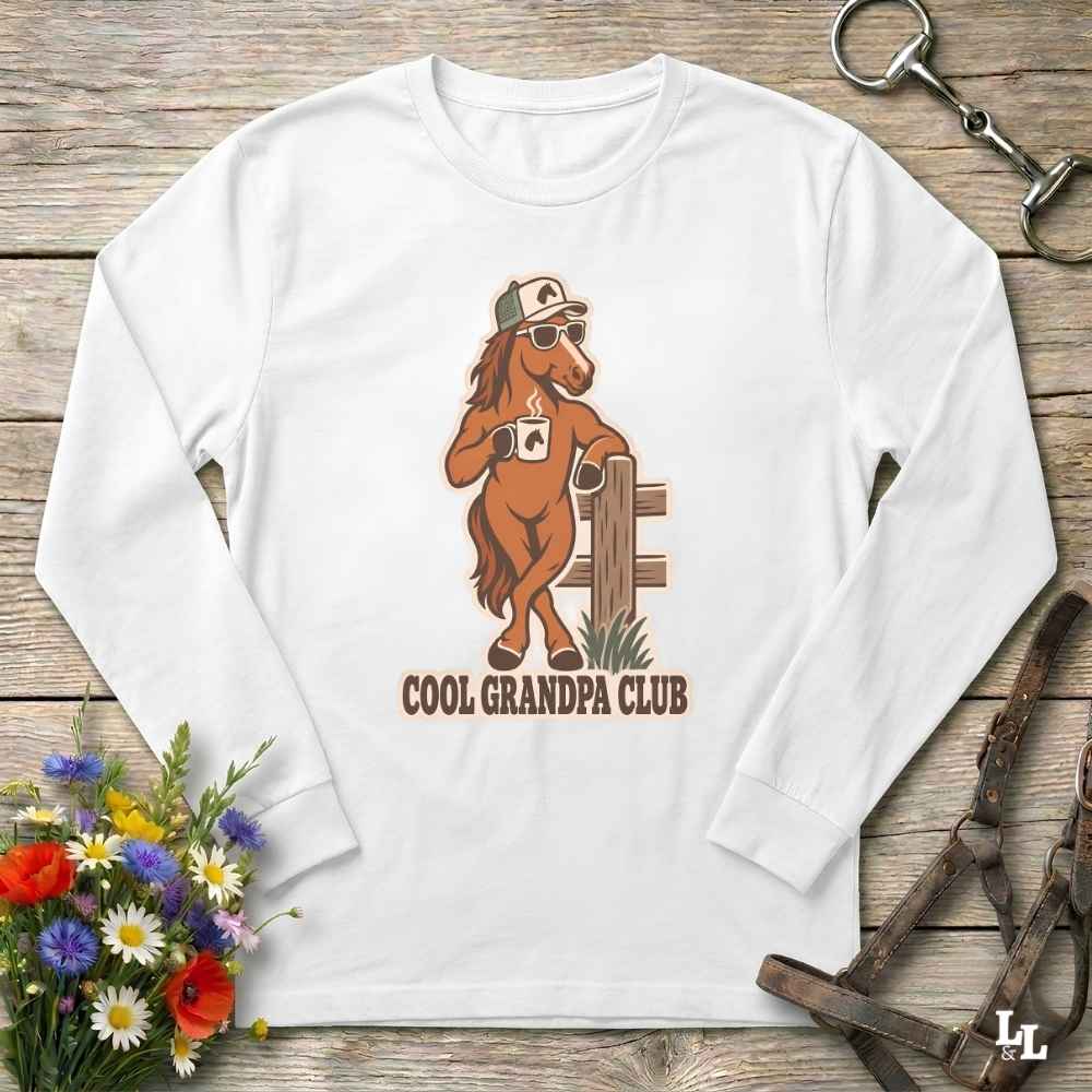 A white long-sleeve t-shirt with a graphic of a brown horse wearing a cap and sunglasses, holding a coffee mug next to a fence. The text 'COOL GRANDPA CLUB' is printed below.