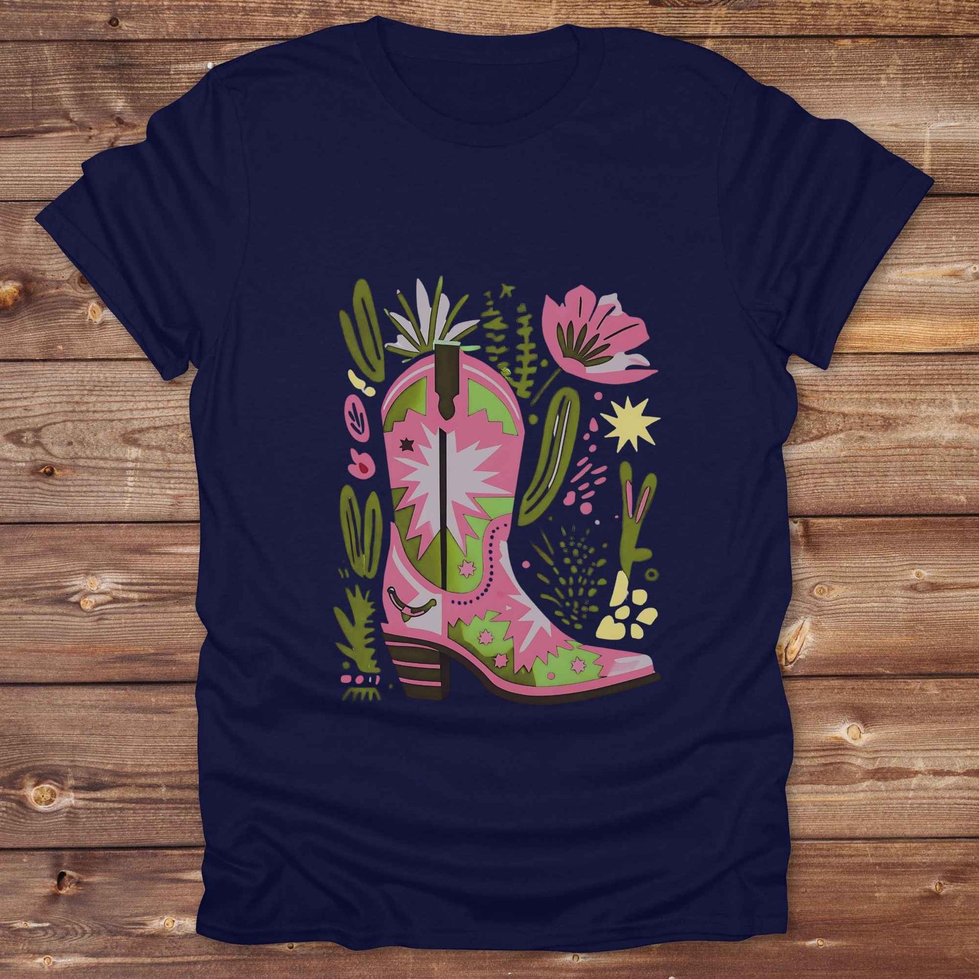 Bright pink and green cowgirl boot printed on a unisex western t-shirt, styled for a boho country vibe. The design is surrounded by floral and cactus illustrations to enhance the desert western theme.
