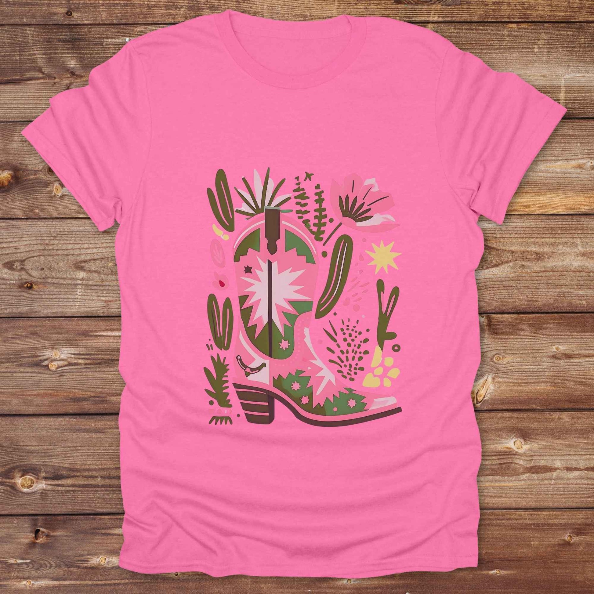 Bright pink and green cowgirl boot printed on a unisex western t-shirt, styled for a boho country vibe. The design is surrounded by floral and cactus illustrations to enhance the desert western theme.