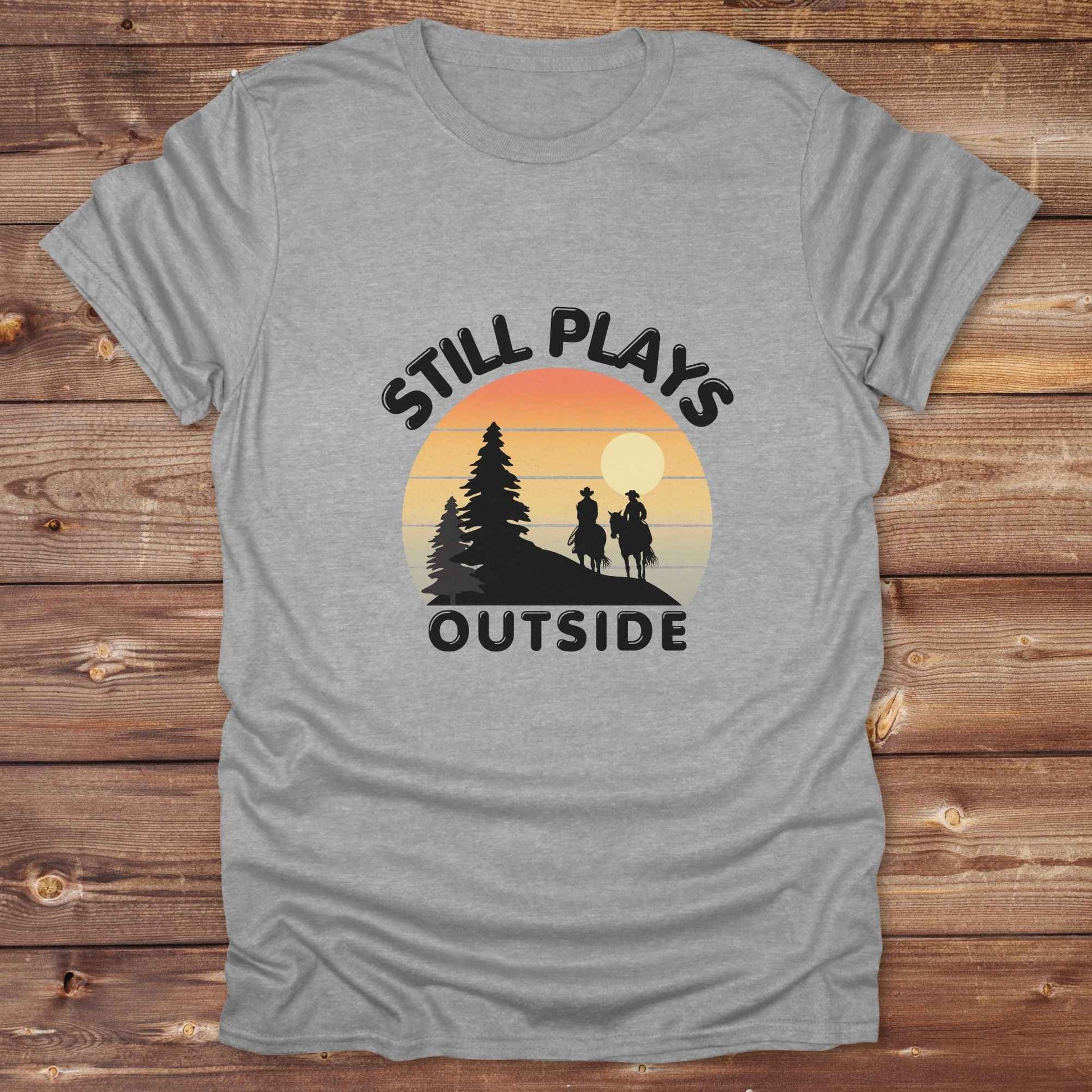 Still plays outside. Funny western t-shirt featuring horse-themed design for cowgirls, cowboys, and equestrians — perfect for rodeo lovers, rustic style fans, and horse people. Unique graphic tee by Lasso and Loom.
