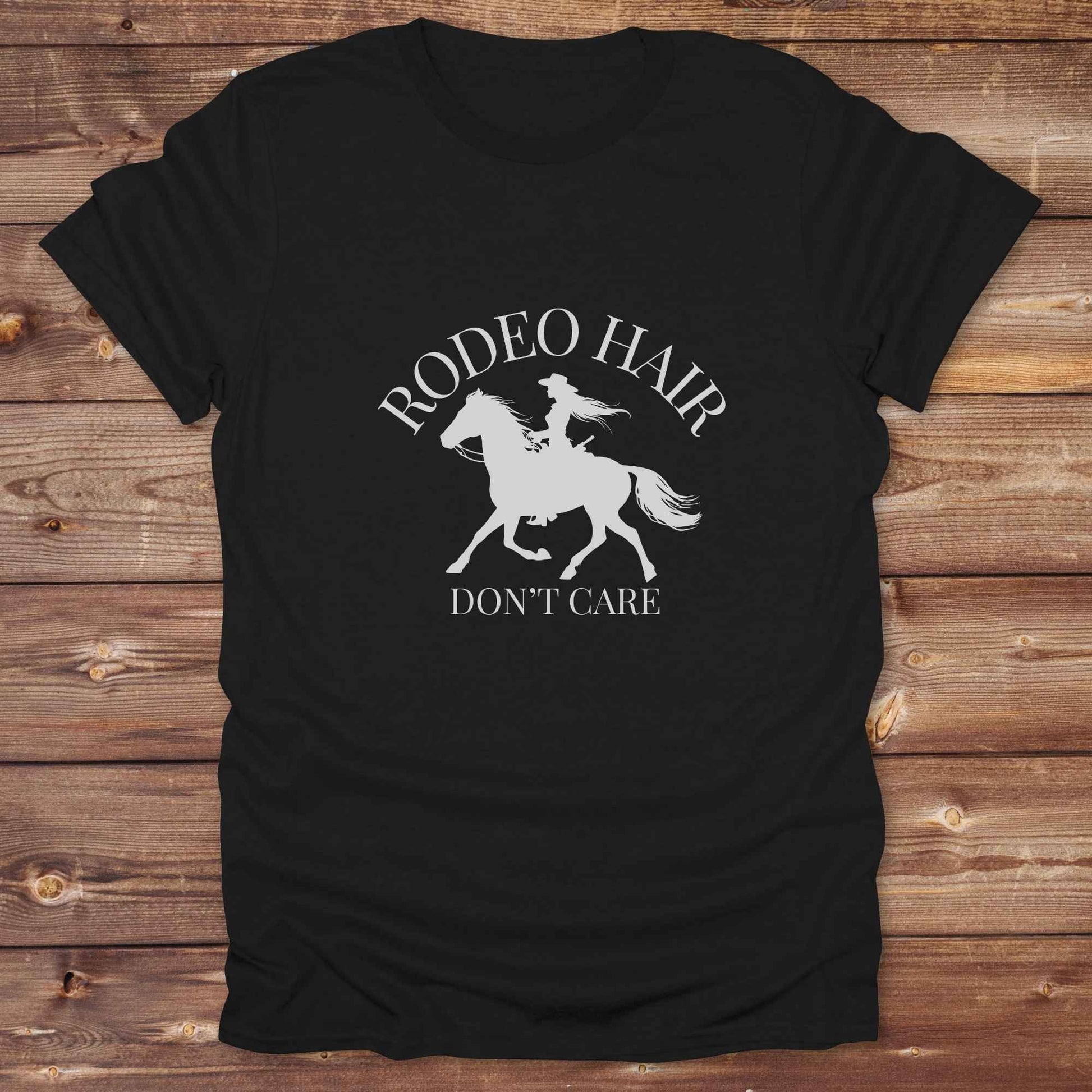 ypography cowgirl t-shirt styled for rodeo lovers and horse girls on rustic wooden background. Trendy cowgirl shirt designed for horse lovers, featuring bold western lettering in graphic style. Horse riding themed t-shirt with country slogan “Rodeo Hair Don’t Care” styled for modern cowgirls.