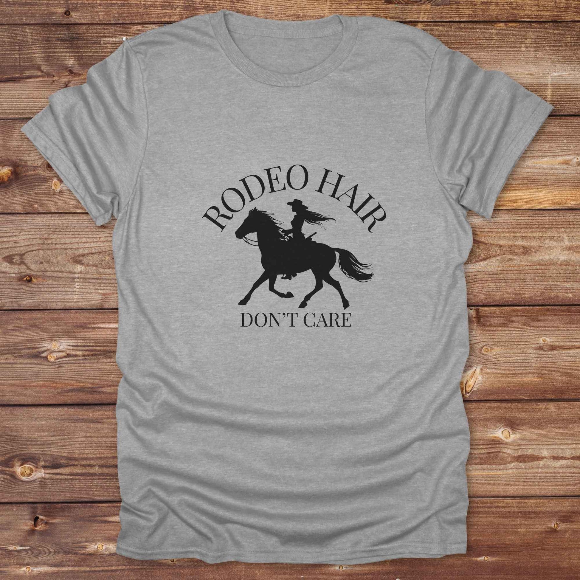 ypography cowgirl t-shirt styled for rodeo lovers and horse girls on rustic wooden background. Trendy cowgirl shirt designed for horse lovers, featuring bold western lettering in graphic style. Horse riding themed t-shirt with country slogan “Rodeo Hair Don’t Care” styled for modern cowgirls.