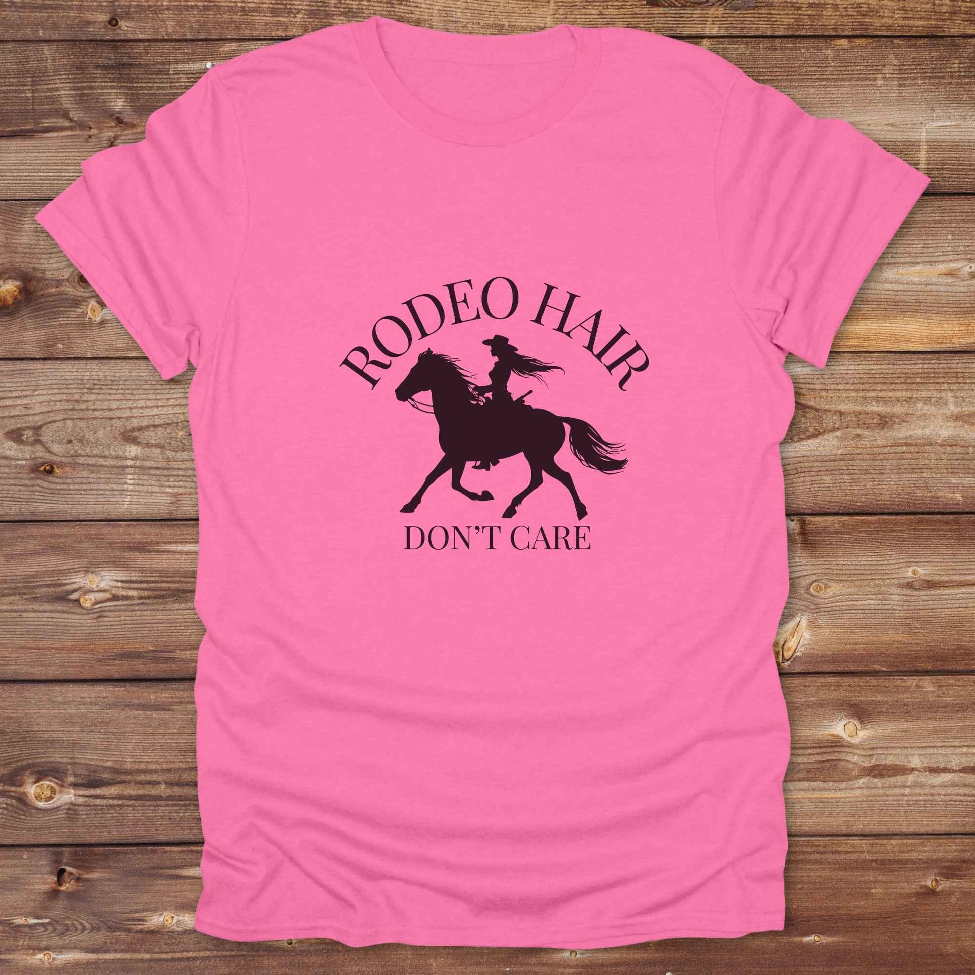 ypography cowgirl t-shirt styled for rodeo lovers and horse girls on rustic wooden background. Trendy cowgirl shirt designed for horse lovers, featuring bold western lettering in graphic style. Horse riding themed t-shirt with country slogan “Rodeo Hair Don’t Care” styled for modern cowgirls.