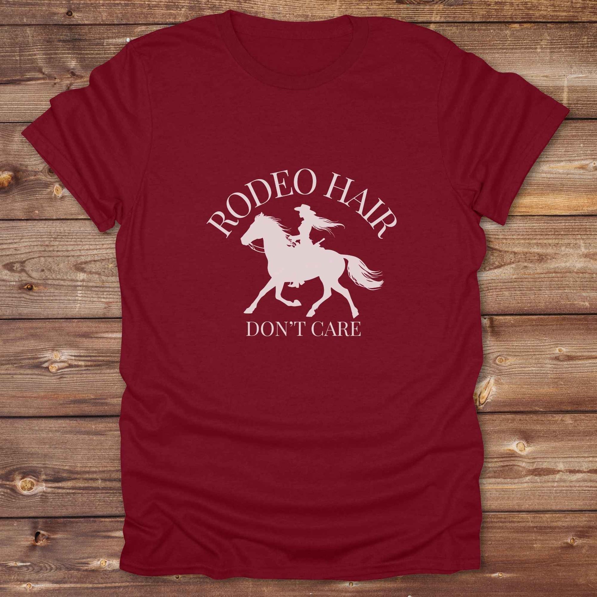 ypography cowgirl t-shirt styled for rodeo lovers and horse girls on rustic wooden background. Trendy cowgirl shirt designed for horse lovers, featuring bold western lettering in graphic style. Horse riding themed t-shirt with country slogan “Rodeo Hair Don’t Care” styled for modern cowgirls.