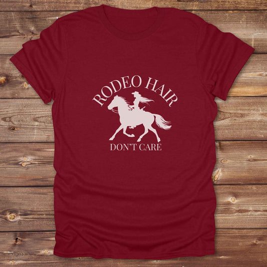 ypography cowgirl t-shirt styled for rodeo lovers and horse girls on rustic wooden background. Trendy cowgirl shirt designed for horse lovers, featuring bold western lettering in graphic style. Horse riding themed t-shirt with country slogan “Rodeo Hair Don’t Care” styled for modern cowgirls.