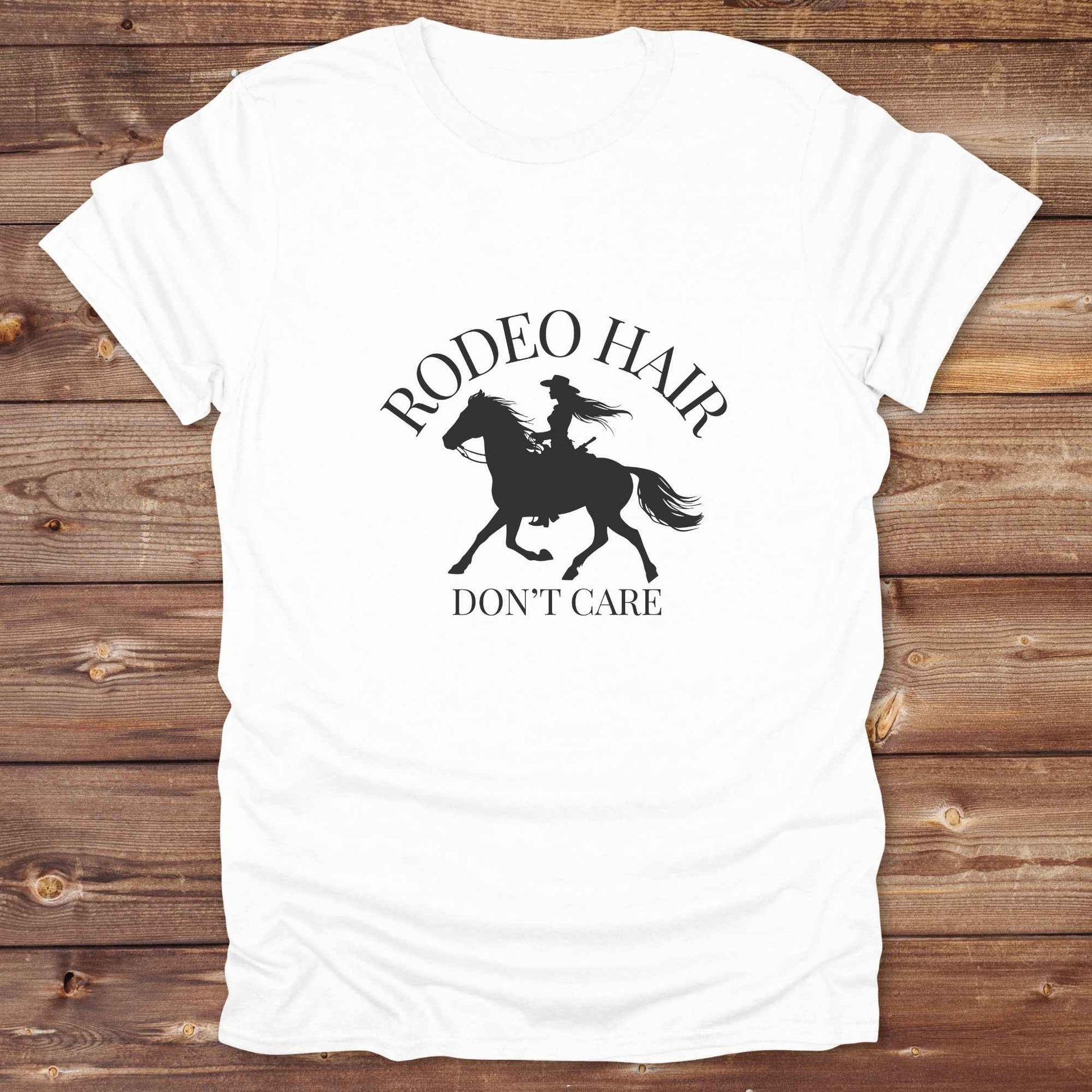ypography cowgirl t-shirt styled for rodeo lovers and horse girls on rustic wooden background. Trendy cowgirl shirt designed for horse lovers, featuring bold western lettering in graphic style. Horse riding themed t-shirt with country slogan “Rodeo Hair Don’t Care” styled for modern cowgirls.