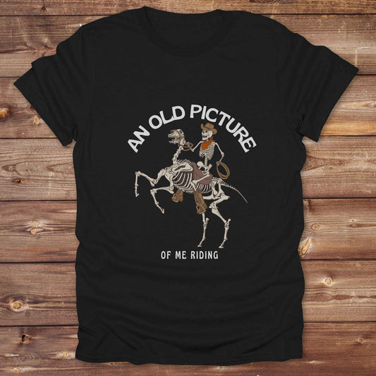 Saddle up with spooky western vibes in this skeleton cowboy “Old Picture of Me Riding” shirt, perfect for rodeo lovers and Halloween humor fans. This cowboy skeleton t-shirt combines retro western style with dark humor, ideal for ranchers, riders, and funny costume alternatives. Make fall fashion unforgettable with this witty, rustic western parody tee featuring bones, boots, and bold cowboy nostalgia.