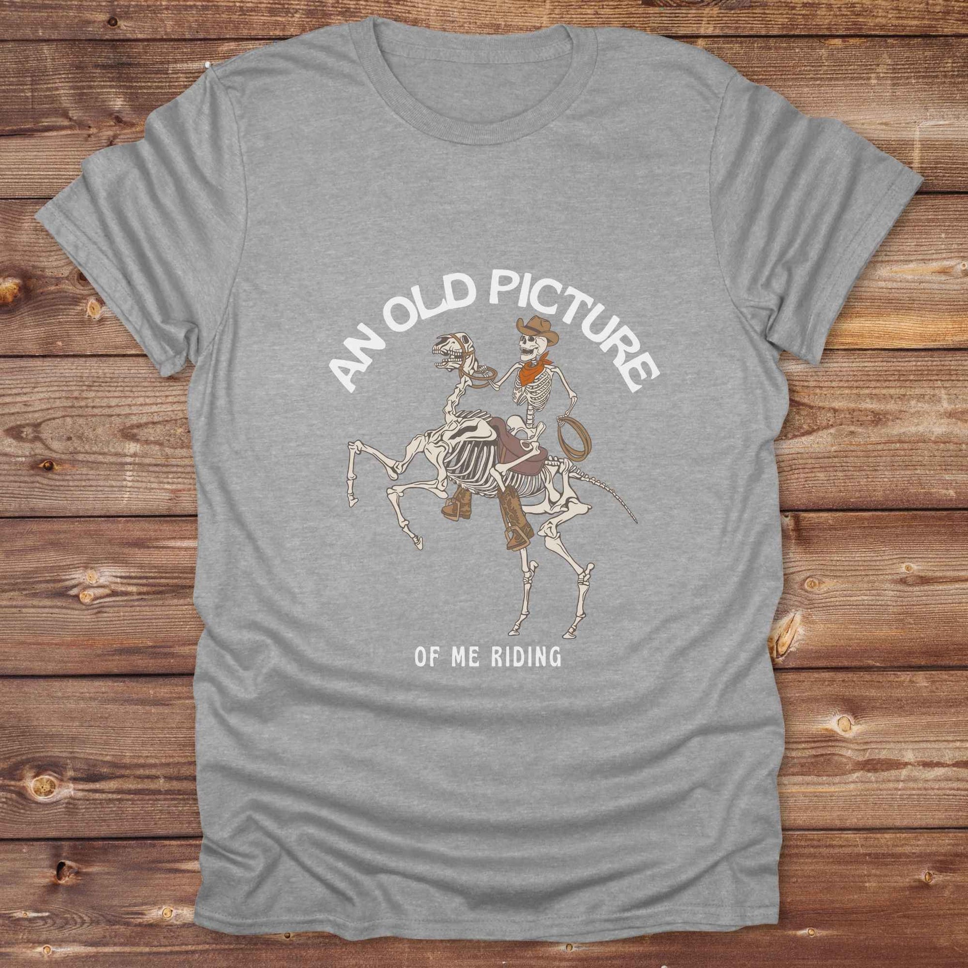 Saddle up with spooky western vibes in this skeleton cowboy “Old Picture of Me Riding” shirt, perfect for rodeo lovers and Halloween humor fans. This cowboy skeleton t-shirt combines retro western style with dark humor, ideal for ranchers, riders, and funny costume alternatives. Make fall fashion unforgettable with this witty, rustic western parody tee featuring bones, boots, and bold cowboy nostalgia.