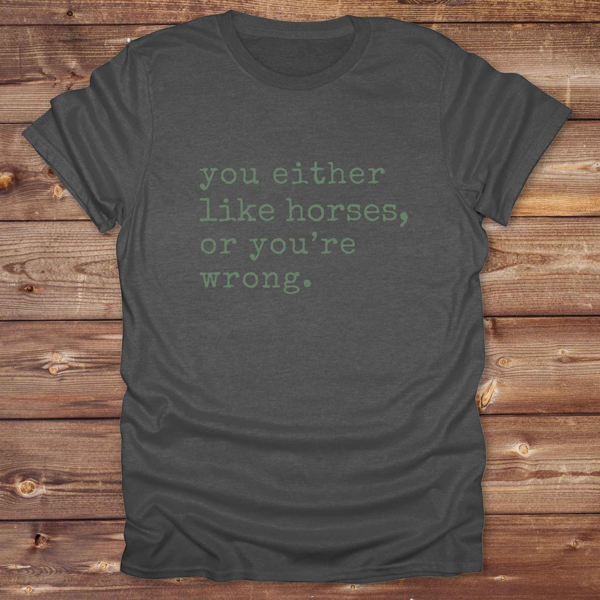 Dark gray t-shirt with green text on a wooden surface. Show your love for horses loud and proud with this funny typography western tee ,perfect for cowgirls, ranchers, and equestrians. 
This “You either like horses or you're wrong” t-shirt is a hilarious must have for horse lovers with sass and sarcasm. Ideal gift for any horse girl or cowboy, this rustic western Gildan tee blends humor with horse life perfectly. Whether you’re mucking stalls or riding trails, this sarcastic horse lover tee is a funny go-to