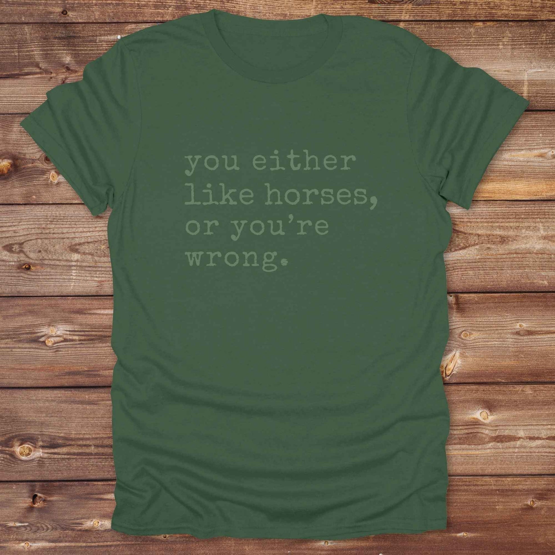 Green t-shirt with text 'you either like horses, or you're wrong.' on a wooden background. Show your love for horses loud and proud with this funny typography western tee ,perfect for cowgirls, ranchers, and equestrians. 
This “You either like horses or you're wrong” t-shirt is a hilarious must have for horse lovers with sass and sarcasm. Ideal gift for any horse girl or cowboy, this rustic western Gildan tee blends humor with horse life perfectly. Whether you’re mucking stalls or riding trails, this sarcas
