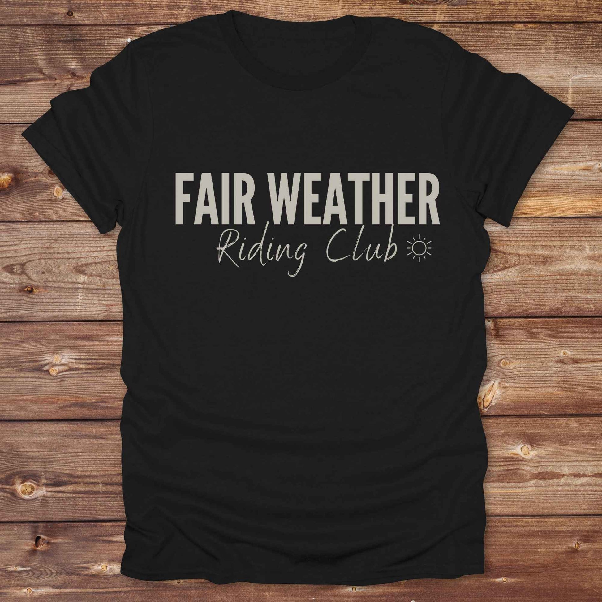 "Fair Weather Riding Club” tee brings western charm and playful equestrian humor together in a bold design that speaks to cowboys and cowgirls alike. erfect for horse lovers who only ride in sunshine. Featuring clean typography and a cute sun icon, it’s the ultimate cowboy core essential for rodeo days, trail rides, or just lounging in the barn. Whether it’s for yourself or as a gift for a fellow rider, this western quote tee adds a sunny twist to any rustic outfit. must have for any modern day trailblazer.