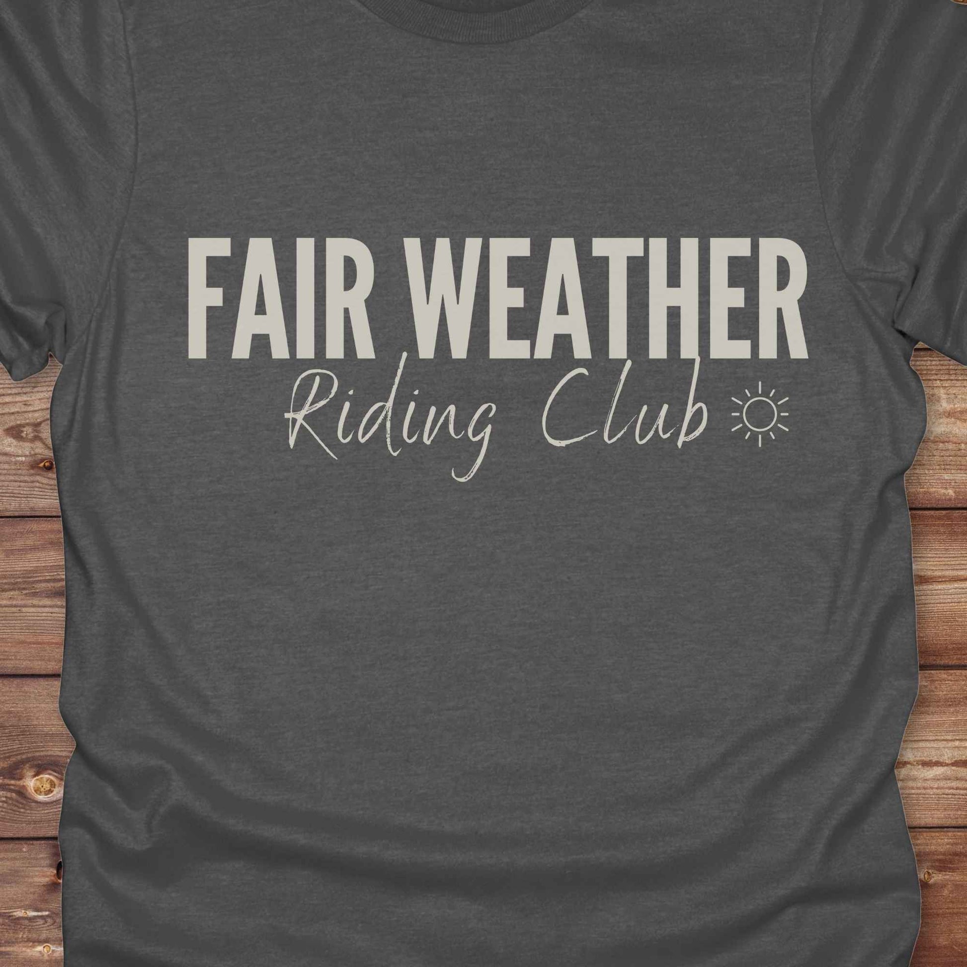 "Fair Weather Riding Club” tee brings western charm and playful equestrian humor together in a bold design that speaks to cowboys and cowgirls alike. erfect for horse lovers who only ride in sunshine. Featuring clean typography and a cute sun icon, it’s the ultimate cowboy core essential for rodeo days, trail rides, or just lounging in the barn. Whether it’s for yourself or as a gift for a fellow rider, this western quote tee adds a sunny twist to any rustic outfit. must have for any modern day trailblazer.