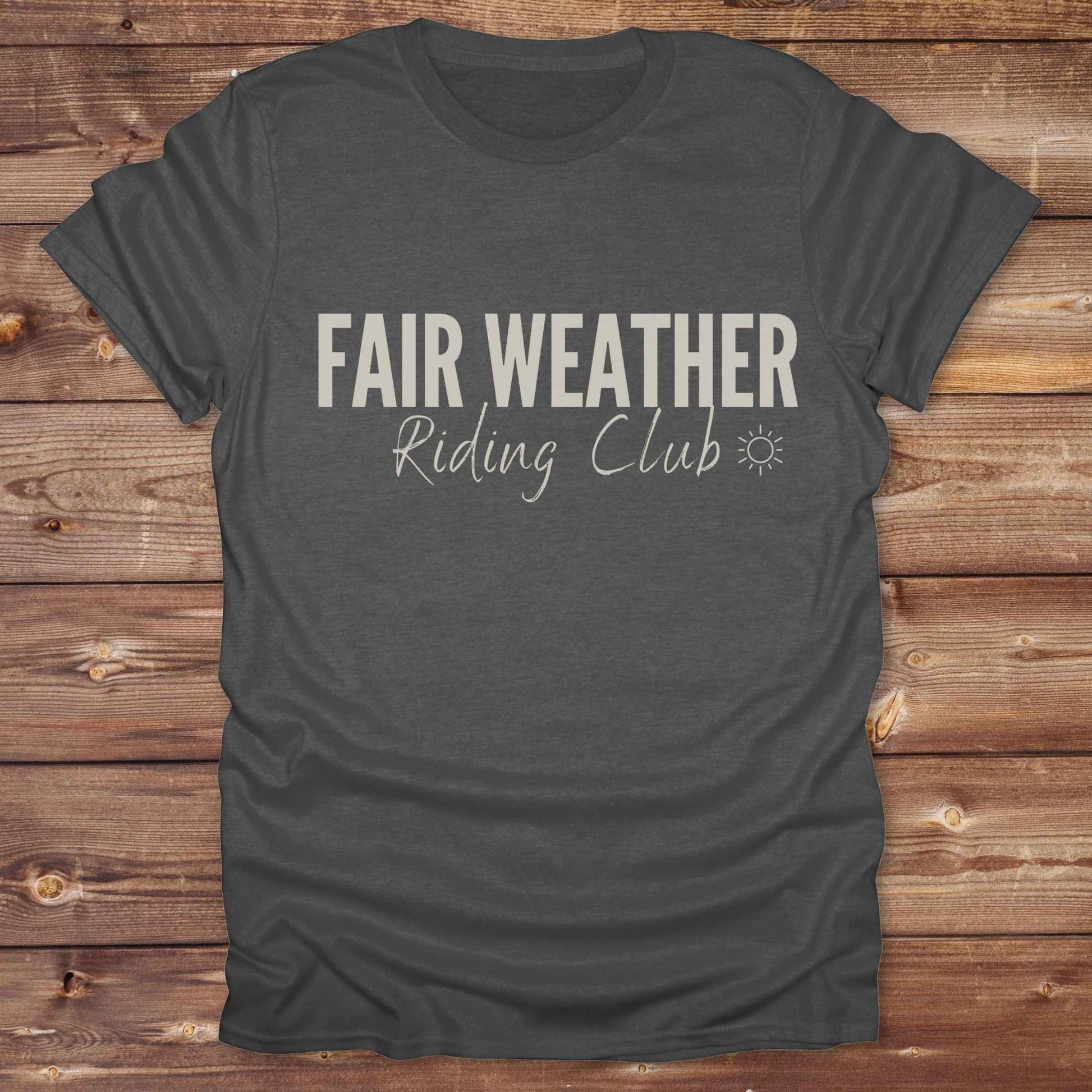 "Fair Weather Riding Club” tee brings western charm and playful equestrian humor together in a bold design that speaks to cowboys and cowgirls alike. erfect for horse lovers who only ride in sunshine. Featuring clean typography and a cute sun icon, it’s the ultimate cowboy core essential for rodeo days, trail rides, or just lounging in the barn. Whether it’s for yourself or as a gift for a fellow rider, this western quote tee adds a sunny twist to any rustic outfit. must have for any modern day trailblazer.