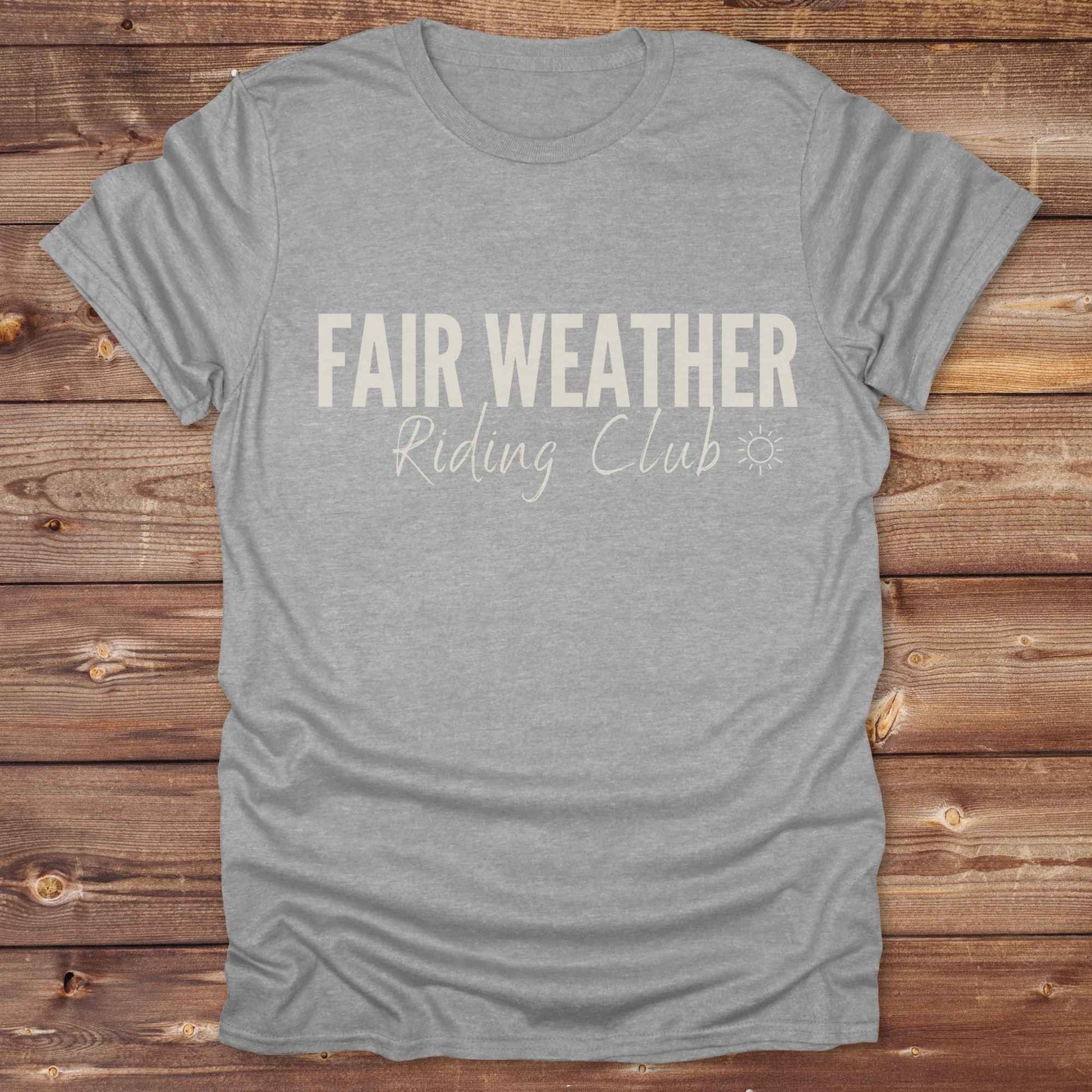 "Fair Weather Riding Club” tee brings western charm and playful equestrian humor together in a bold design that speaks to cowboys and cowgirls alike. erfect for horse lovers who only ride in sunshine. Featuring clean typography and a cute sun icon, it’s the ultimate cowboy core essential for rodeo days, trail rides, or just lounging in the barn. Whether it’s for yourself or as a gift for a fellow rider, this western quote tee adds a sunny twist to any rustic outfit. must have for any modern day trailblazer.