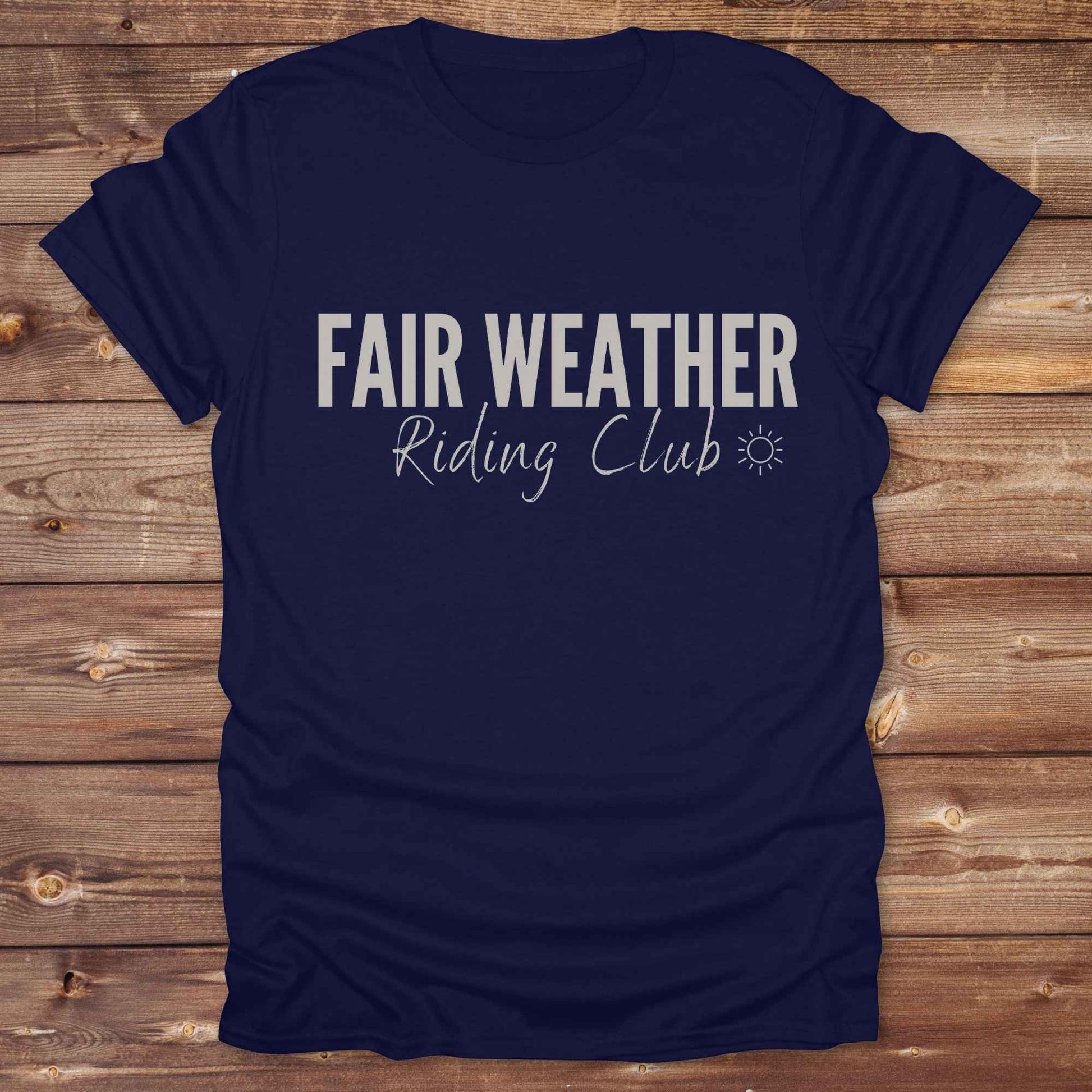 "Fair Weather Riding Club” tee brings western charm and playful equestrian humor together in a bold design that speaks to cowboys and cowgirls alike. erfect for horse lovers who only ride in sunshine. Featuring clean typography and a cute sun icon, it’s the ultimate cowboy core essential for rodeo days, trail rides, or just lounging in the barn. Whether it’s for yourself or as a gift for a fellow rider, this western quote tee adds a sunny twist to any rustic outfit. must have for any modern day trailblazer.