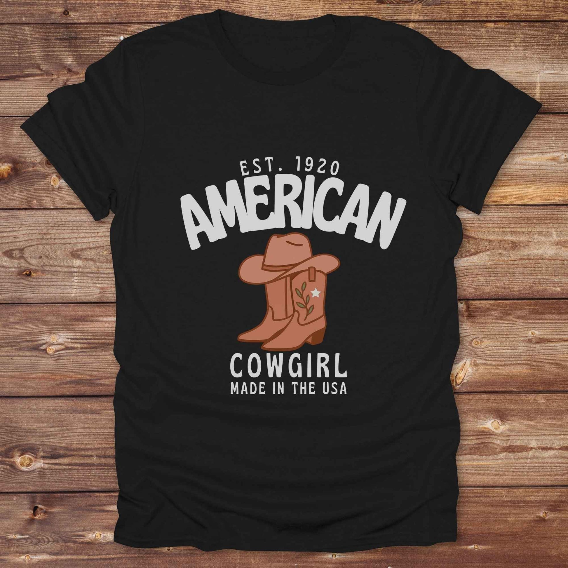 This American Cowgirl T-Shirt is the perfect mix of bold western pride and boho rodeo style. Featuring a rustic boot and hat graphic, it's made for country girls who live for rodeo season and horse rides. It’s a statement piece for cowgirls, country lovers, and western fashion fans alike. Whether you’re gifting it for a birthday or styling it for your next state fair, this tee brings serious cowboy core energy to your closet.  A must have for horse lovers.