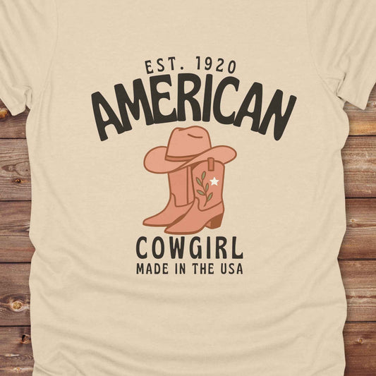 This American Cowgirl T-Shirt is the perfect mix of bold western pride and boho rodeo style. Featuring a rustic boot and hat graphic, it's made for country girls who live for rodeo season and horse rides. It’s a statement piece for cowgirls, country lovers, and western fashion fans alike. Whether you’re gifting it for a birthday or styling it for your next state fair, this tee brings serious cowboy core energy to your closet.  A must have for horse lovers.