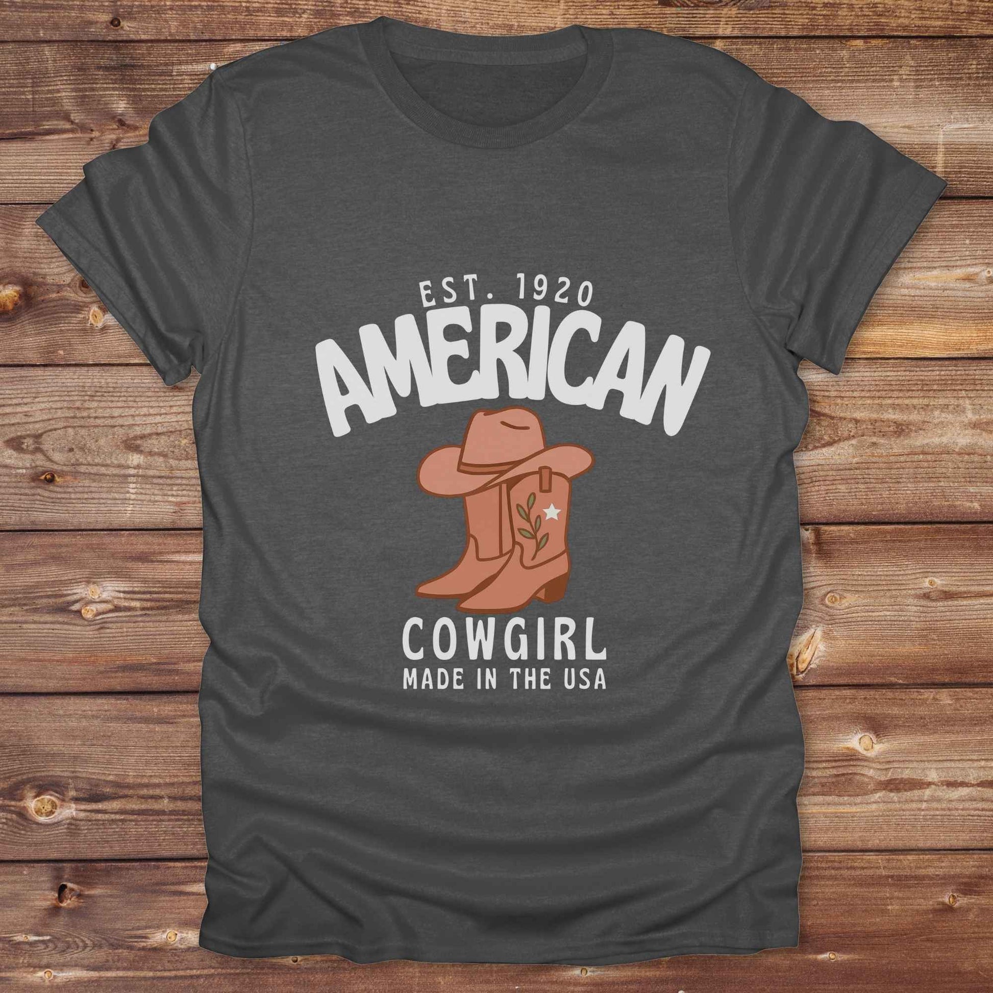This American Cowgirl T-Shirt is the perfect mix of bold western pride and boho rodeo style. Featuring a rustic boot and hat graphic, it's made for country girls who live for rodeo season and horse rides. It’s a statement piece for cowgirls, country lovers, and western fashion fans alike. Whether you’re gifting it for a birthday or styling it for your next state fair, this tee brings serious cowboy core energy to your closet.  A must have for horse lovers.
