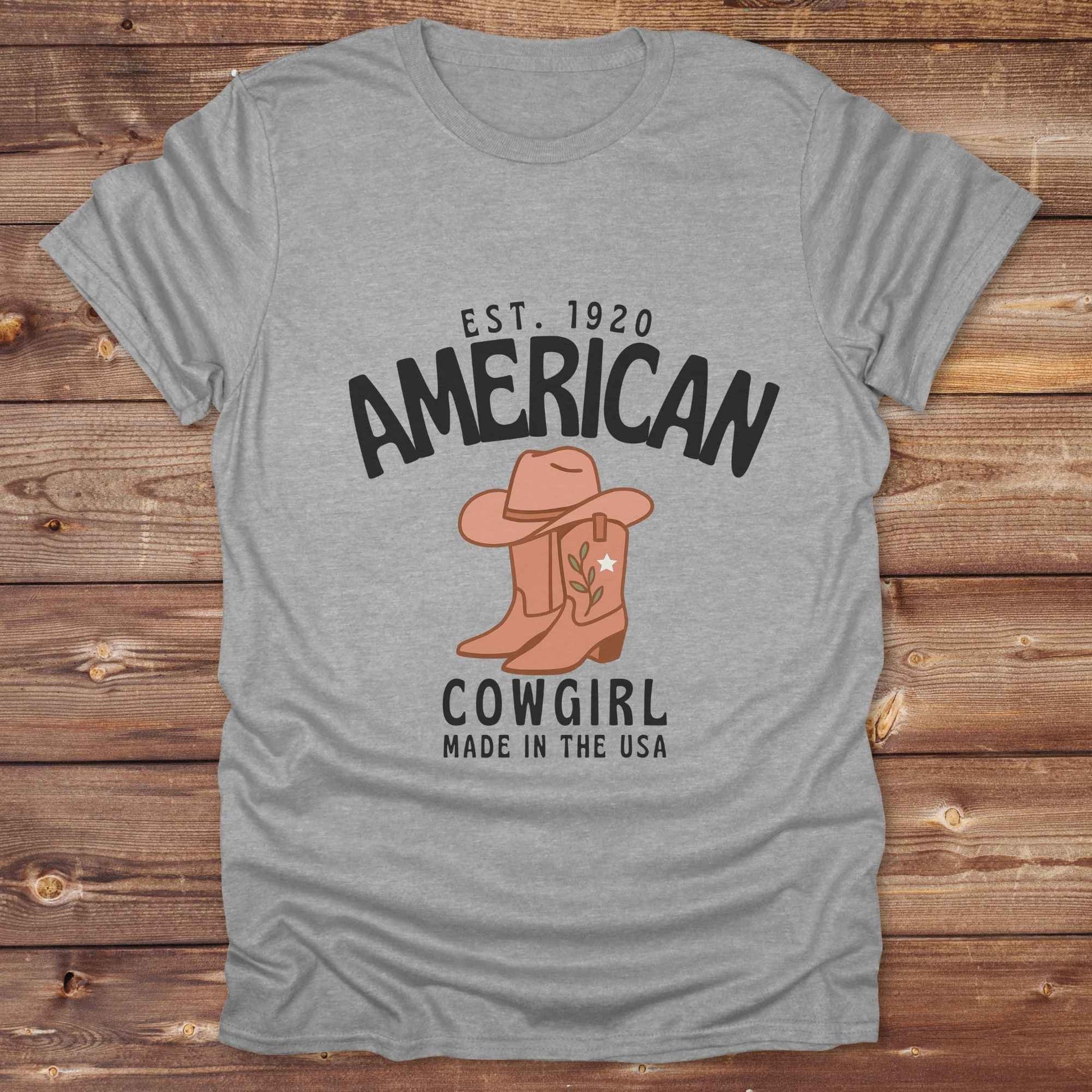 This American Cowgirl T-Shirt is the perfect mix of bold western pride and boho rodeo style. Featuring a rustic boot and hat graphic, it's made for country girls who live for rodeo season and horse rides. It’s a statement piece for cowgirls, country lovers, and western fashion fans alike. Whether you’re gifting it for a birthday or styling it for your next state fair, this tee brings serious cowboy core energy to your closet.  A must have for horse lovers.