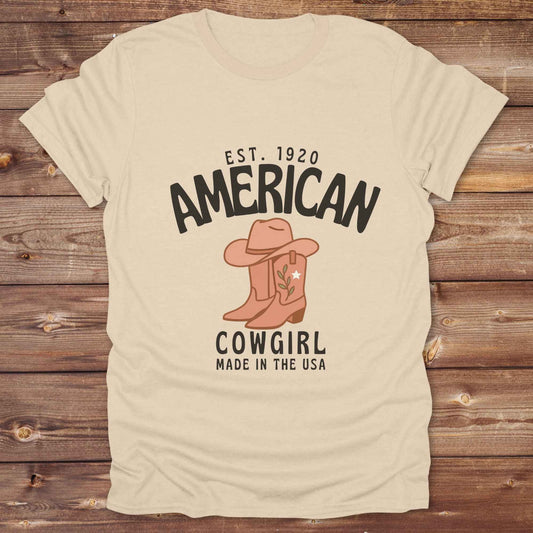 This American Cowgirl T-Shirt is the perfect mix of bold western pride and boho rodeo style. Featuring a rustic boot and hat graphic, it's made for country girls who live for rodeo season and horse rides. It’s a statement piece for cowgirls, country lovers, and western fashion fans alike. Whether you’re gifting it for a birthday or styling it for your next state fair, this tee brings serious cowboy core energy to your closet.  A must have for horse lovers.