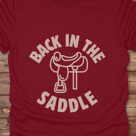 Our "Back in the Saddle" t-shirt is the perfect western-style graphic tee for cowboys and cowgirls who love horseback riding, rodeo culture, and rustic country fashion. Featuring a clean saddle illustration and retro western typography, this shirt blends comfort and character, making it ideal for ranch wear, horse lovers, and rodeo enthusiasts. Whether you're heading to a country concert, festival, or barn, this tee stands out. Makes a great gift for horse riders, western fans or anyone getting back riding