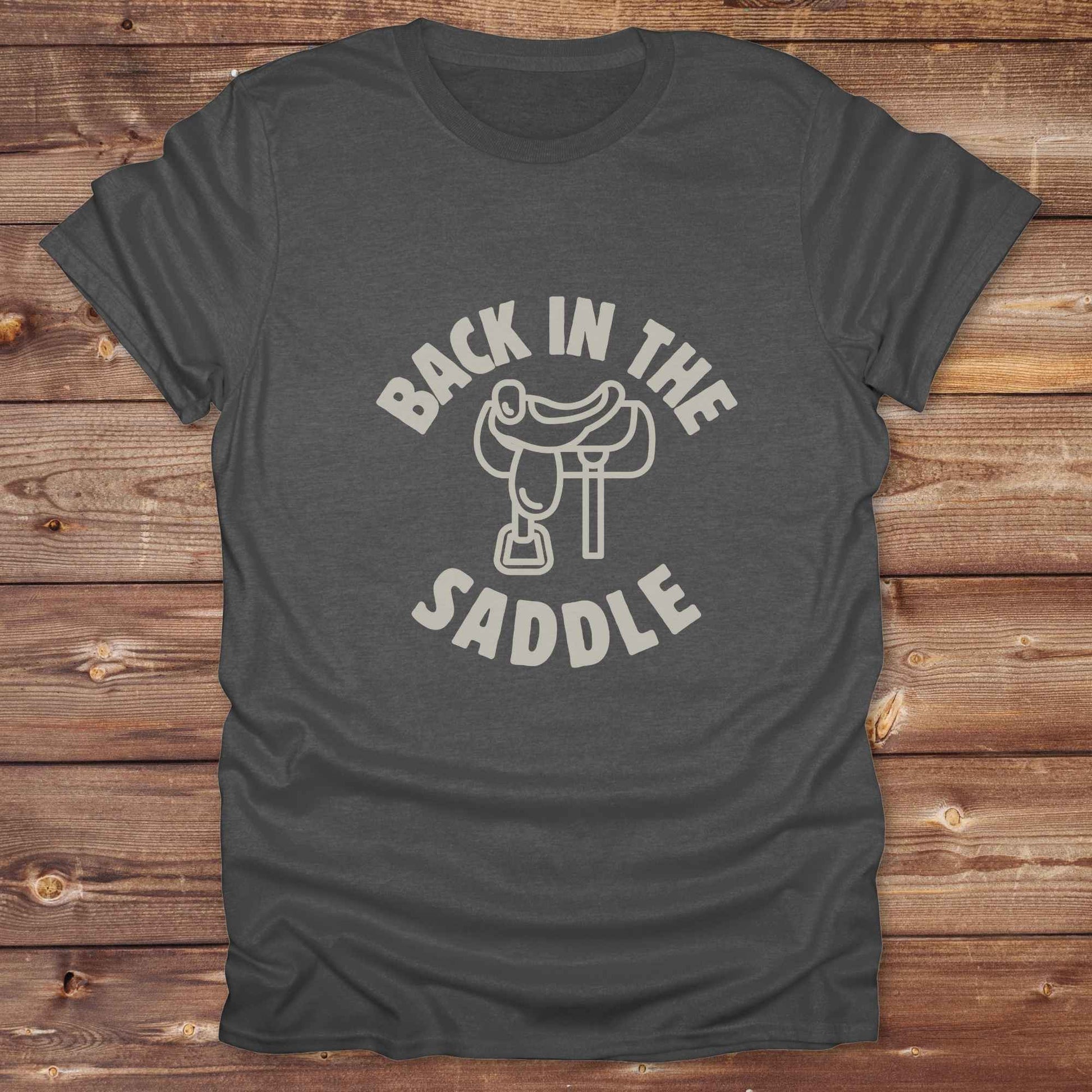 Our "Back in the Saddle" t-shirt is the perfect western-style graphic tee for cowboys and cowgirls who love horseback riding, rodeo culture, and rustic country fashion. Featuring a clean saddle illustration and retro western typography, this shirt blends comfort and character, making it ideal for ranch wear, horse lovers, and rodeo enthusiasts. Whether you're heading to a country concert, festival, or barn, this tee stands out. Makes a great gift for horse riders, western fans or anyone getting back riding