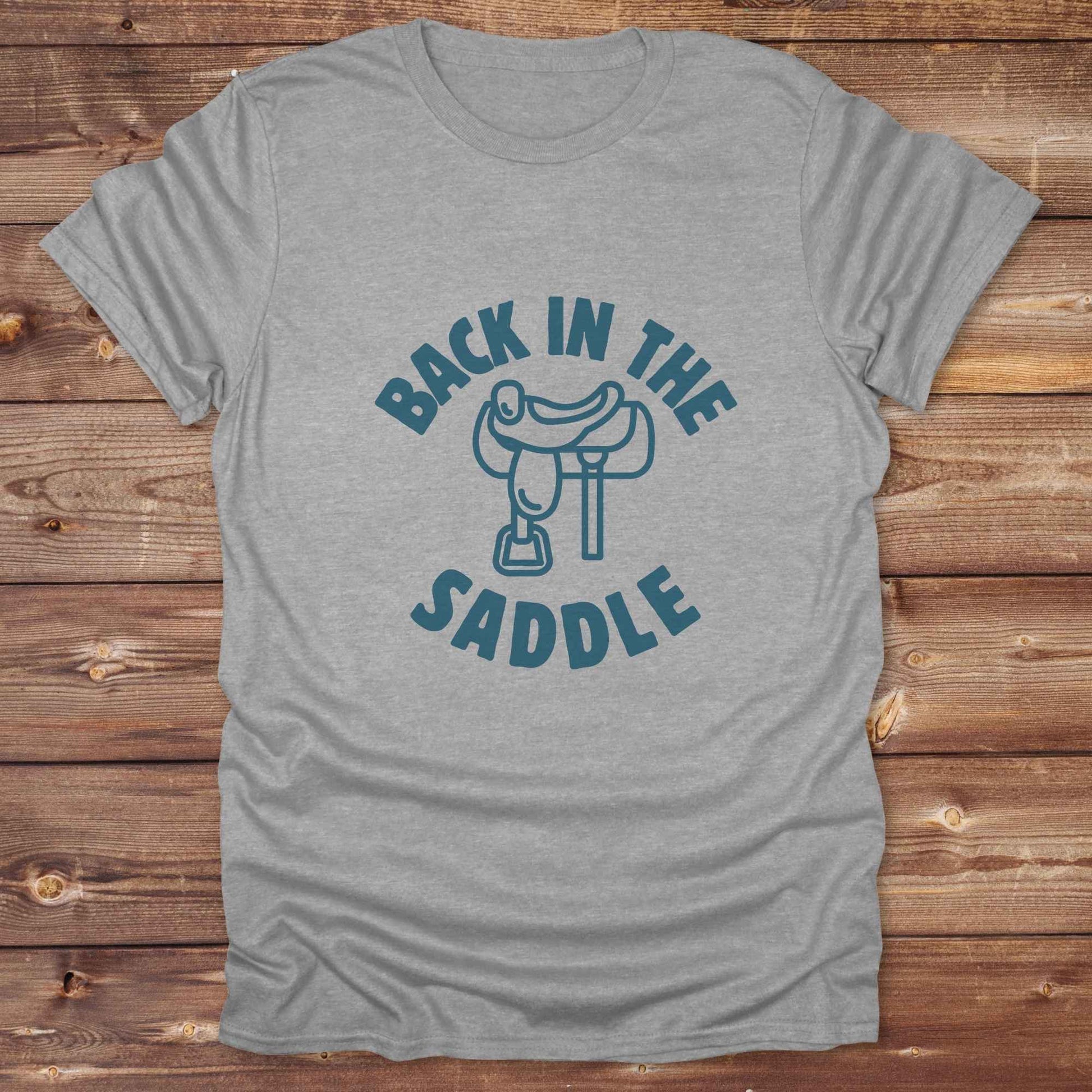 Our "Back in the Saddle" t-shirt is the perfect western-style graphic tee for cowboys and cowgirls who love horseback riding, rodeo culture, and rustic country fashion. Featuring a clean saddle illustration and retro western typography, this shirt blends comfort and character, making it ideal for ranch wear, horse lovers, and rodeo enthusiasts. Whether you're heading to a country concert, festival, or barn, this tee stands out. Makes a great gift for horse riders, western fans or anyone getting back riding