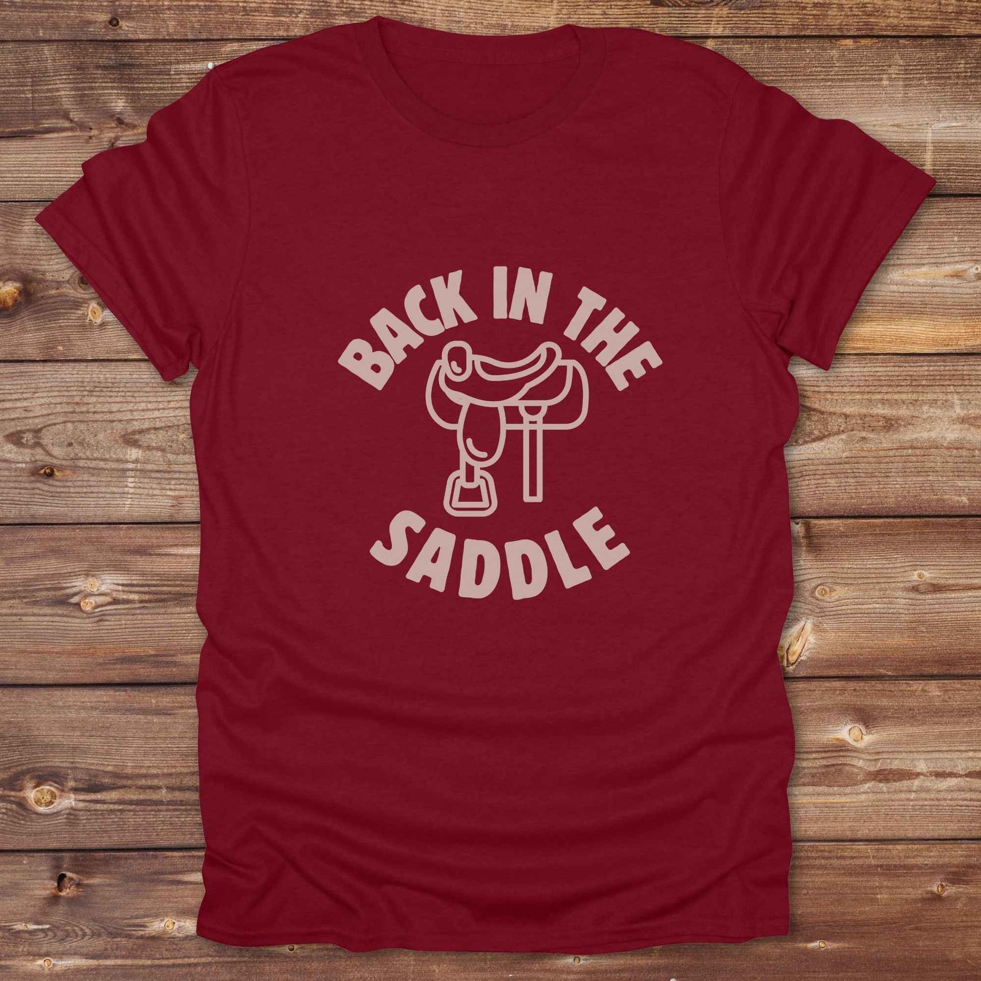 Our "Back in the Saddle" t-shirt is the perfect western-style graphic tee for cowboys and cowgirls who love horseback riding, rodeo culture, and rustic country fashion. Featuring a clean saddle illustration and retro western typography, this shirt blends comfort and character, making it ideal for ranch wear, horse lovers, and rodeo enthusiasts. Whether you're heading to a country concert, festival, or barn, this tee stands out. Makes a great gift for horse riders, western fans or anyone getting back riding