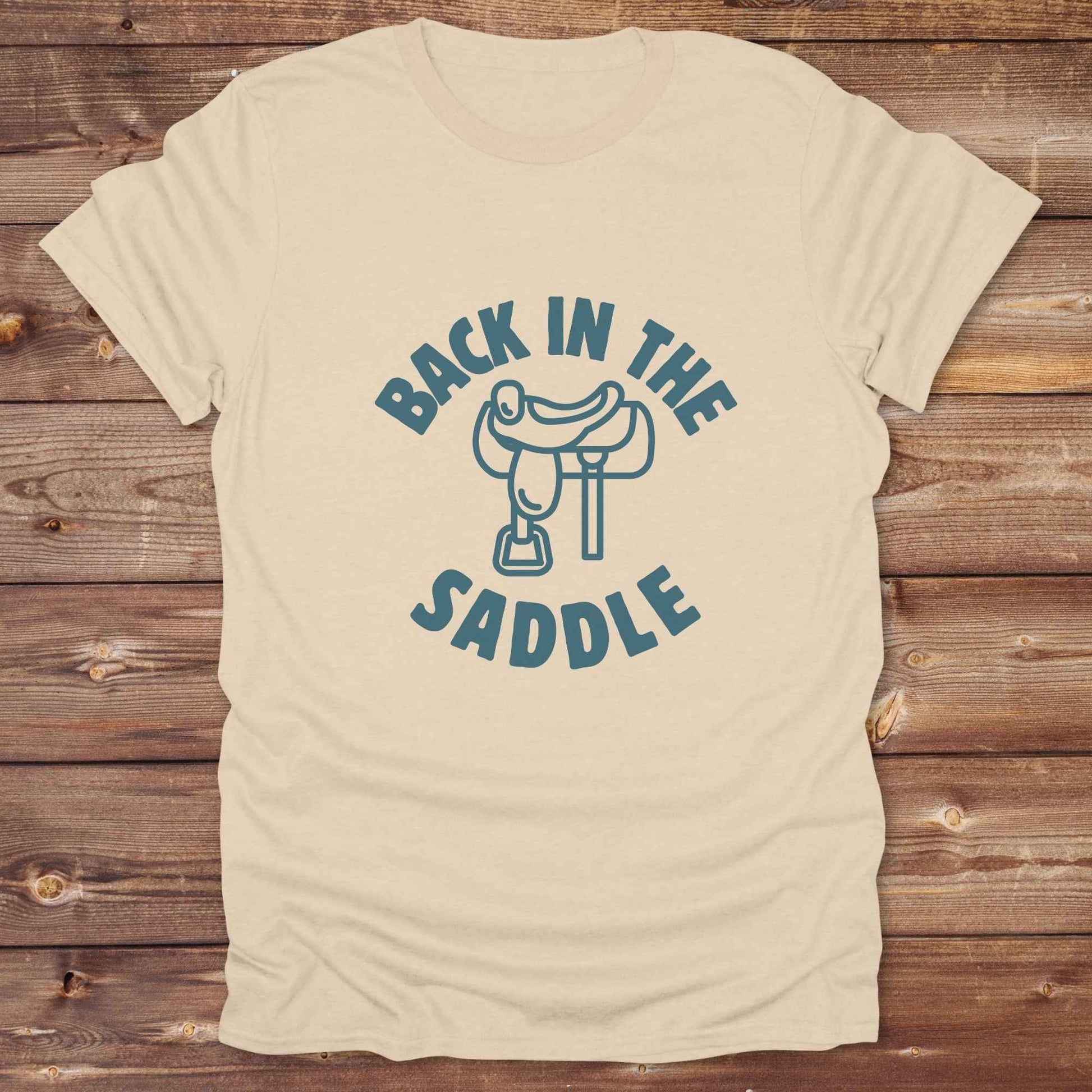 Our "Back in the Saddle" t-shirt is the perfect western-style graphic tee for cowboys and cowgirls who love horseback riding, rodeo culture, and rustic country fashion. Featuring a clean saddle illustration and retro western typography, this shirt blends comfort and character, making it ideal for ranch wear, horse lovers, and rodeo enthusiasts. Whether you're heading to a country concert, festival, or barn, this tee stands out. Makes a great gift for horse riders, western fans or anyone getting back riding
