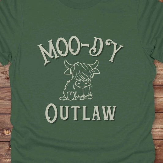 Meet the “Moo-Dy Outlaw” tee from Lasso and Loom a perfect mix of western sass and farmyard fun. Featuring a hand drawn moody Highland cow and outlaw typography, this western graphic tee is made for cowgirls, cowboys, and everyone who rides through life with a little attitude. It's ideal for rodeos, ranch days, and social media selfies with rustic vibes and comfort in every stitch. Whether you're shopping for yourself or gifting a cow lover with a sense of humor, this shirt is guaranteed to wrangle smiles