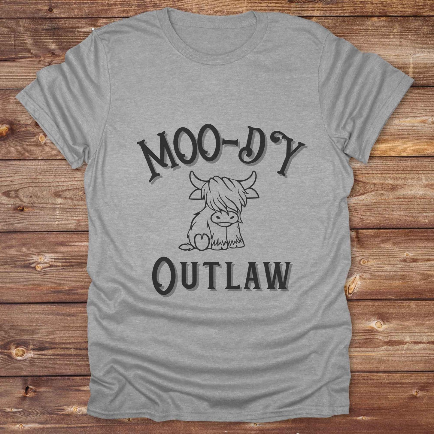 Meet the “Moo-Dy Outlaw” tee from Lasso and Loom a perfect mix of western sass and farmyard fun. Featuring a hand drawn moody Highland cow and outlaw typography, this western graphic tee is made for cowgirls, cowboys, and everyone who rides through life with a little attitude. It's ideal for rodeos, ranch days, and social media selfies with rustic vibes and comfort in every stitch. Whether you're shopping for yourself or gifting a cow lover with a sense of humor, this shirt is guaranteed to wrangle smiles