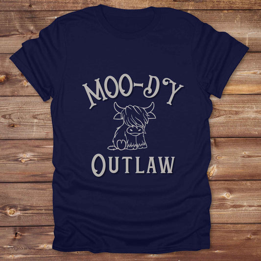 Meet the “Moo-Dy Outlaw” tee from Lasso and Loom a perfect mix of western sass and farmyard fun. Featuring a hand drawn moody Highland cow and outlaw typography, this western graphic tee is made for cowgirls, cowboys, and everyone who rides through life with a little attitude. It's ideal for rodeos, ranch days, and social media selfies with rustic vibes and comfort in every stitch. Whether you're shopping for yourself or gifting a cow lover with a sense of humor, this shirt is guaranteed to wrangle smiles