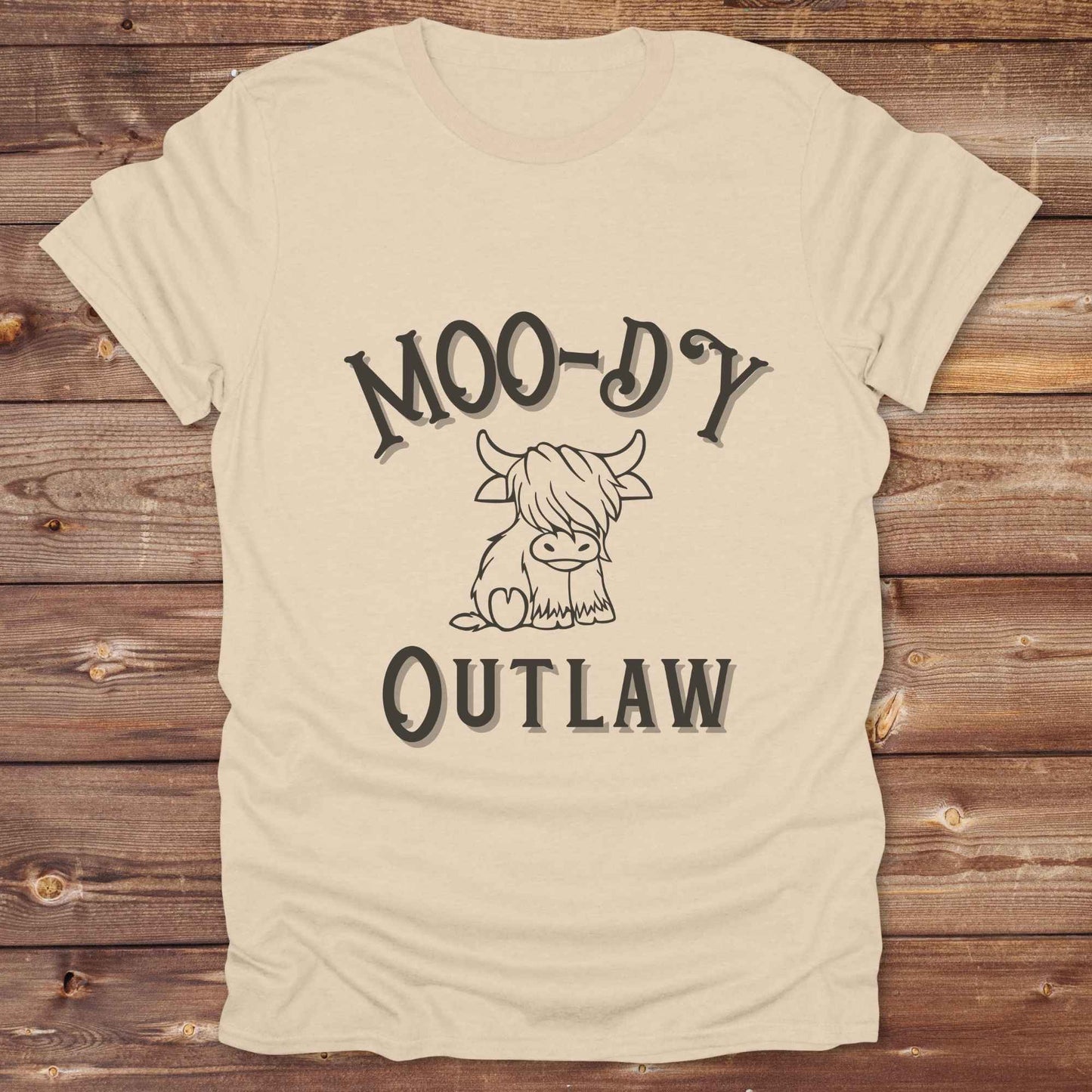 Meet the “Moo-Dy Outlaw” tee from Lasso and Loom a perfect mix of western sass and farmyard fun. Featuring a hand drawn moody Highland cow and outlaw typography, this western graphic tee is made for cowgirls, cowboys, and everyone who rides through life with a little attitude. It's ideal for rodeos, ranch days, and social media selfies with rustic vibes and comfort in every stitch. Whether you're shopping for yourself or gifting a cow lover with a sense of humor, this shirt is guaranteed to wrangle smiles