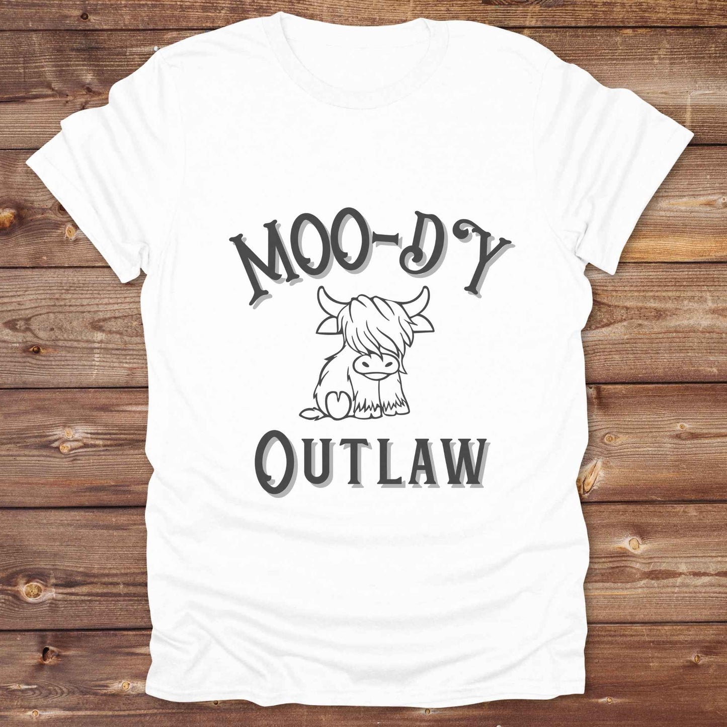 Meet the “Moo-Dy Outlaw” tee from Lasso and Loom a perfect mix of western sass and farmyard fun. Featuring a hand drawn moody Highland cow and outlaw typography, this western graphic tee is made for cowgirls, cowboys, and everyone who rides through life with a little attitude. It's ideal for rodeos, ranch days, and social media selfies with rustic vibes and comfort in every stitch. Whether you're shopping for yourself or gifting a cow lover with a sense of humor, this shirt is guaranteed to wrangle smiles