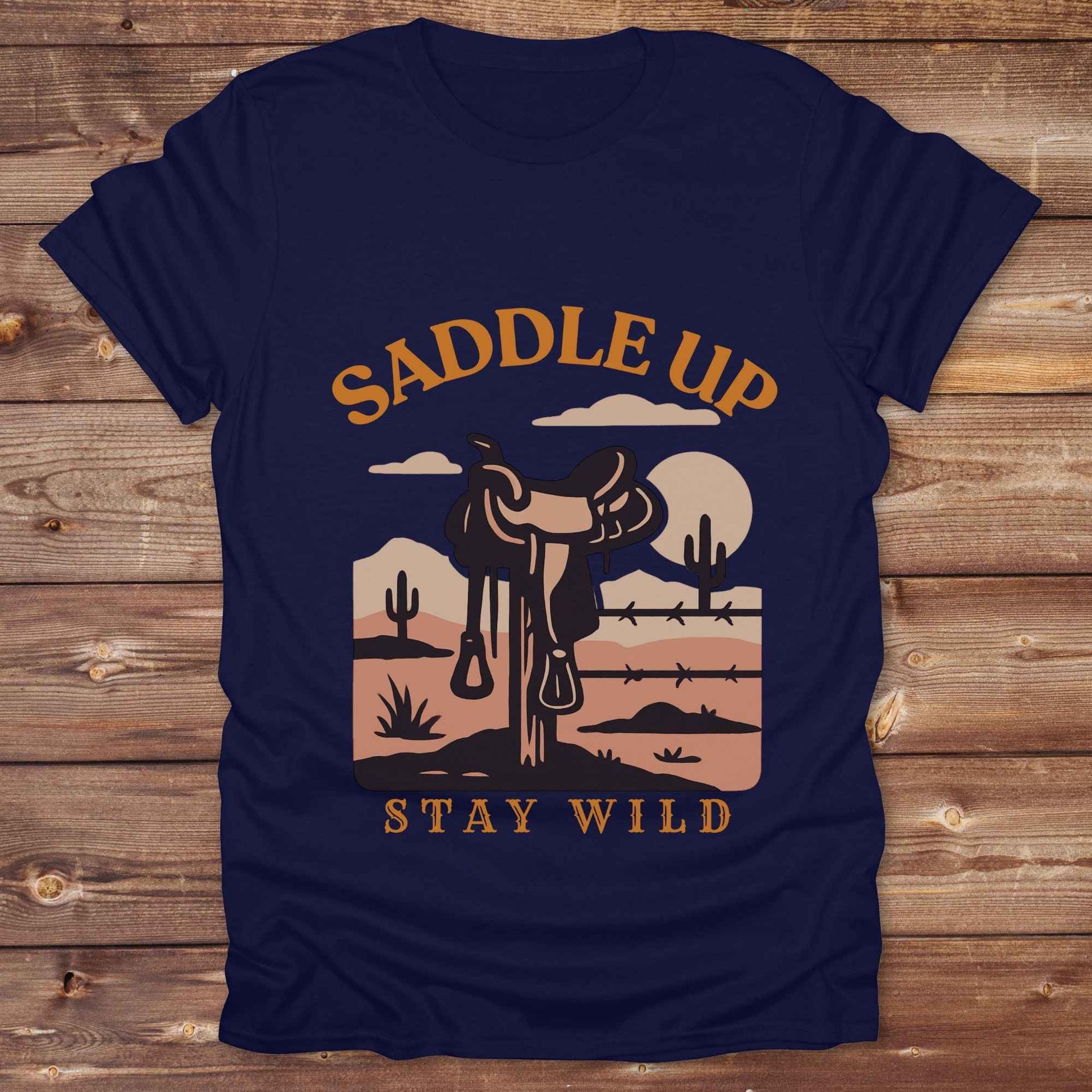 Saddle Up Stay Wild western t-shirt features a bold desert sunset graphic with a classic saddle and western landscape. Perfect for cowgirls, cowboys, and horse lovers, this rustic tee blends adventure with comfort and country charm. Whether you're heading to a rodeo, trail ride, or simply embracing your wild side, this shirt offers a soft fit and bold design. Designed for western wear fans, equestrians, and country souls, it's a must have for anyone who lives the saddle life.