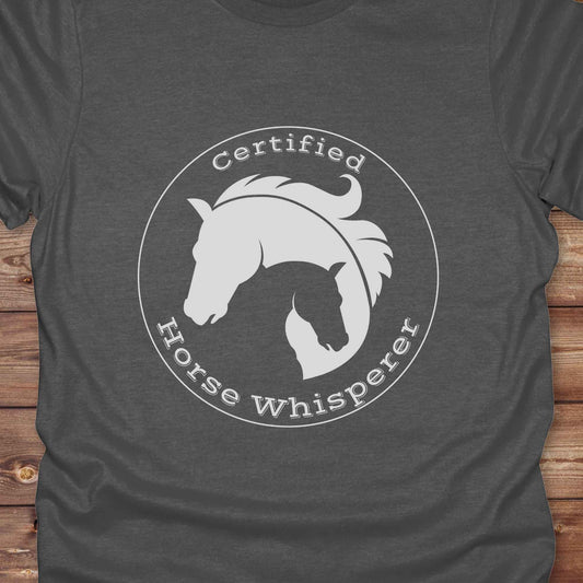 Certified Horse Whisperer T-Shirt is the perfect blend of rustic charm and equestrian elegance. Designed for horse lovers, cowboys, cowgirls, and trainers, this soft unisex graphic tee showcases a minimalist silhouette of two horses within a bold “Certified Horse Whisperer” typographic circle. It's a great gift for birthdays, rodeo fans, western riders, and anyone practicing natural horsemanship or quiet leadership. Conversation starter at the barn, rodeo, trail ride, or farmer’s market. Loved by riders.