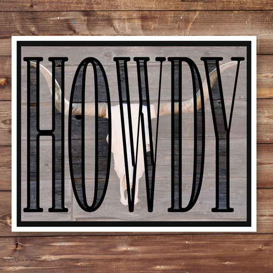 Western style wall art featuring bold "Howdy" typography over a rustic longhorn skull image on a wooden background. Printable cowboy aesthetic art with a bull skull and large "Howdy" lettering, ideal for farmhouse or country homes. Southwestern decor.