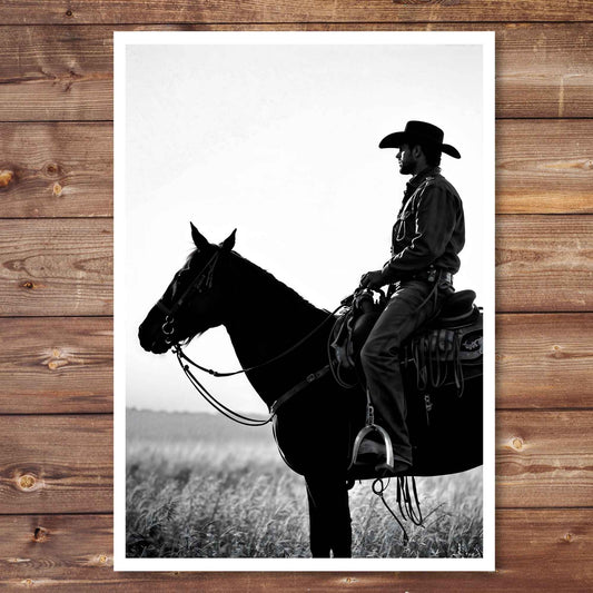Black and white silhouette of a cowboy on horseback against a plain background