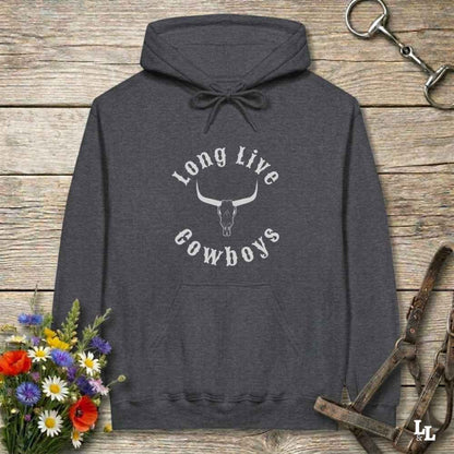 A dark heather gray hoodie with a white graphic reading 'Long Live Cowboys' around a steer skull, laid flat on a rustic wood plank background with flowers and horse tack props.