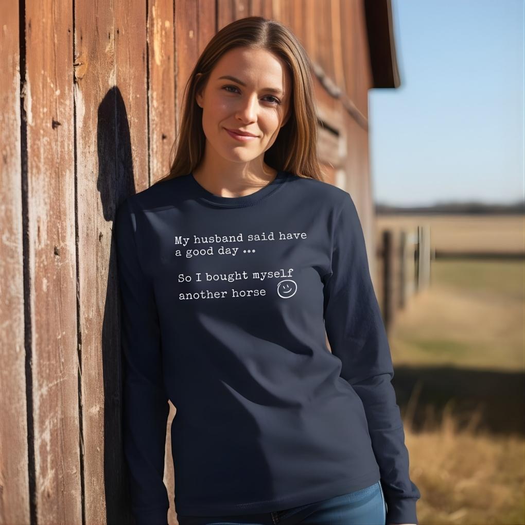 Woman wearing a navy blue sweatshirt with text standing against a wooden barn wall. My Husband Said to have a Good Day Long Sleeve Tee for Horse Lovers, Trail Riding Tee