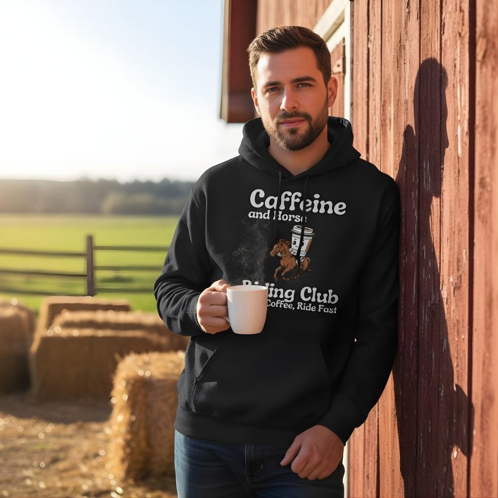 Man wearing a black hoodie with text, holding a mug, standing in front of hay bales and a wooden building. Coffee Riding Club Hoodie for Horse Lovers, Trail back Riding Apparel