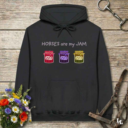 Black hoodie with 'Horses are my JAM' text and jelly jar graphics on a wooden surface with floral and equestrian equipment.
