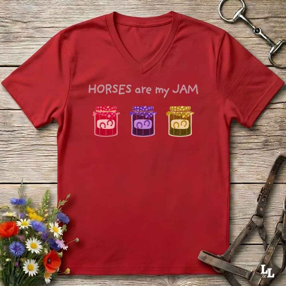 A red V-neck t-shirt with the text 'HORSES are my JAM' and three colorful jars of horse treats, laid flat on a rustic wooden background with equestrian accessories and flowers.