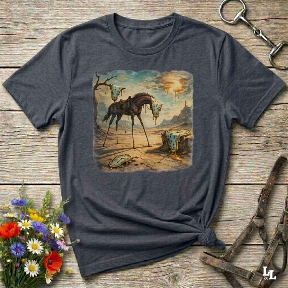 A dark heather gray graphic t-shirt laid flat on a rustic wooden surface, styled with equestrian accessories and a small bouquet of flowers. The t-shirt features a vintage-style illustration of a skeletal horse standing in a desolate landscape.
